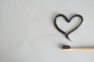 Black charcoal toothpaste shaped like a heart next to a toothbrush