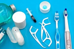 Dental floss picks, floss container, mouthwash, and toothbrushes laid out on a blue background