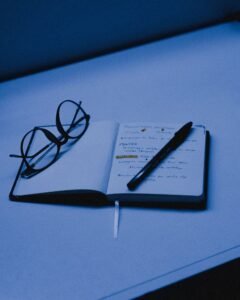 Open notebook with handwritten notes and glasses