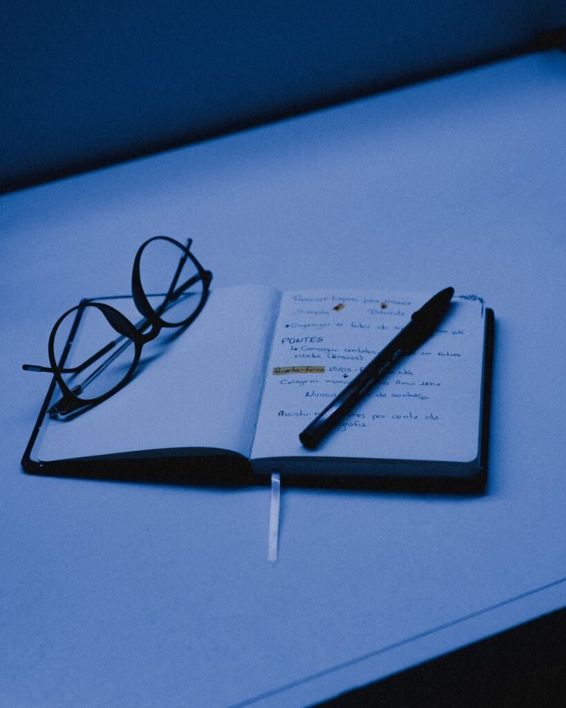 Open notebook with handwritten notes and glasses