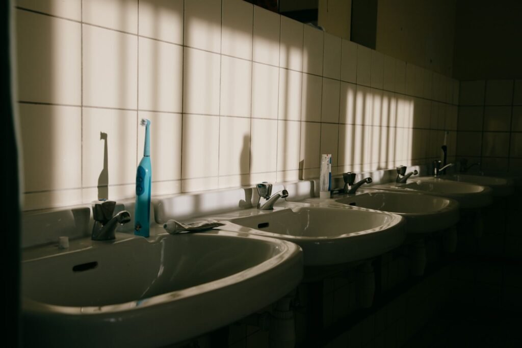 Sunlit bathroom sinks with a toothbrush and toothpaste
