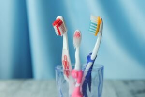 Three toothbrushes in a cup against a blue background
