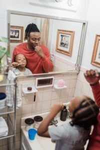 Family brushing teeth together in a bathroom mirror