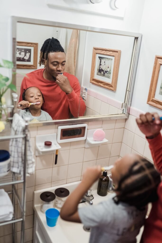 Family brushing teeth together in a bathroom mirror