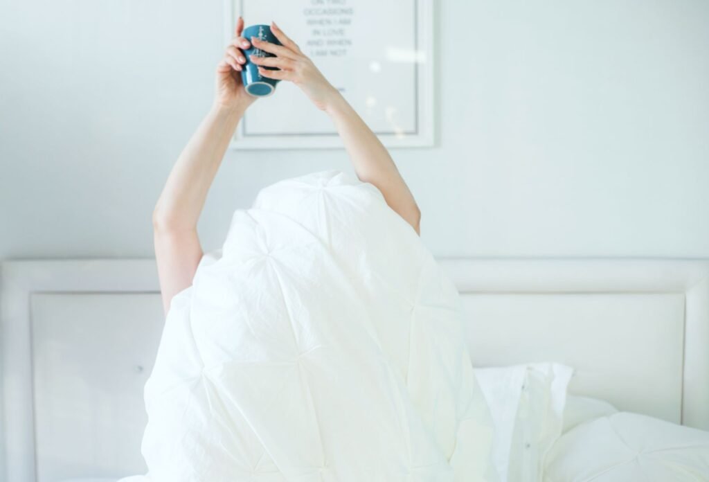 Person waking up and stretching in bed with morning light