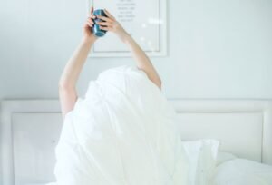 Person waking up and stretching in bed with morning light