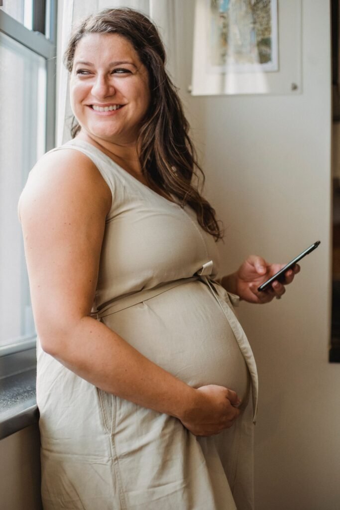 Pregnant woman smiling by a sunlit window