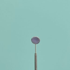 Minimalist dental tool against a teal background