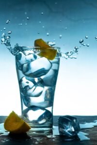 Glass of ice water splashing, representing tooth sensitivity from whitening strips