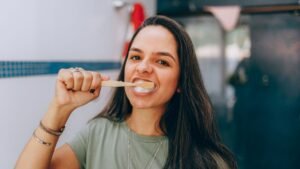 Person brushing their teeth with a bamboo toothbrush in a bright bathroom