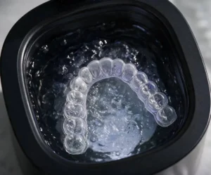 Clear aligner inside the water tank of an ultrasonic retainer cleaner during a cleaning cycle